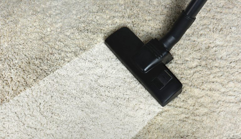 close-up view of cleaning white carpet with professional vacuum cleaner